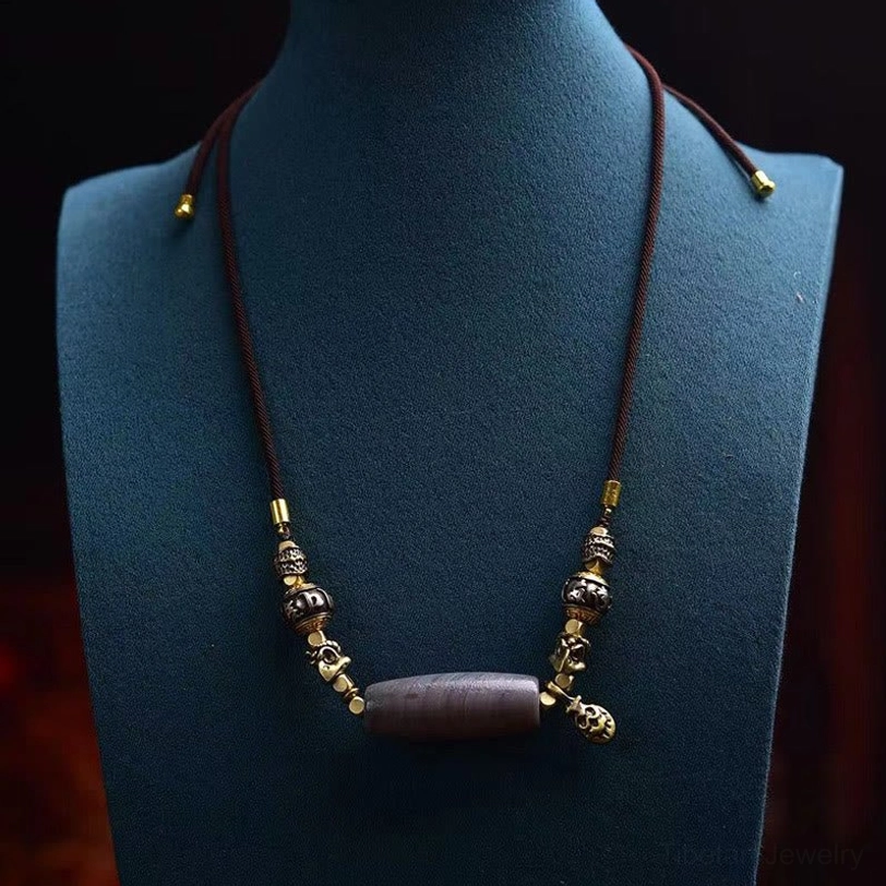 Tibetan dzi bead necklace displayed on mannequin showing full length wear with dark brown rope and bell pendant
