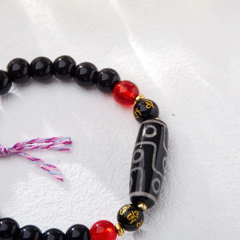 Single nine-eye dzi bead bracelet showing intricate white eye patterns and gold spacers
