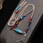 Nine-eye turquoise dzi bead necklace with copper accents on dark wooden surface, authentic Tibetan pendant jewelry