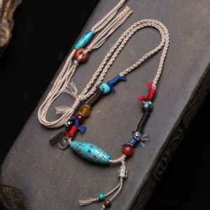 Nine-eye turquoise dzi bead necklace with copper accents on dark wooden surface, authentic Tibetan pendant jewelry