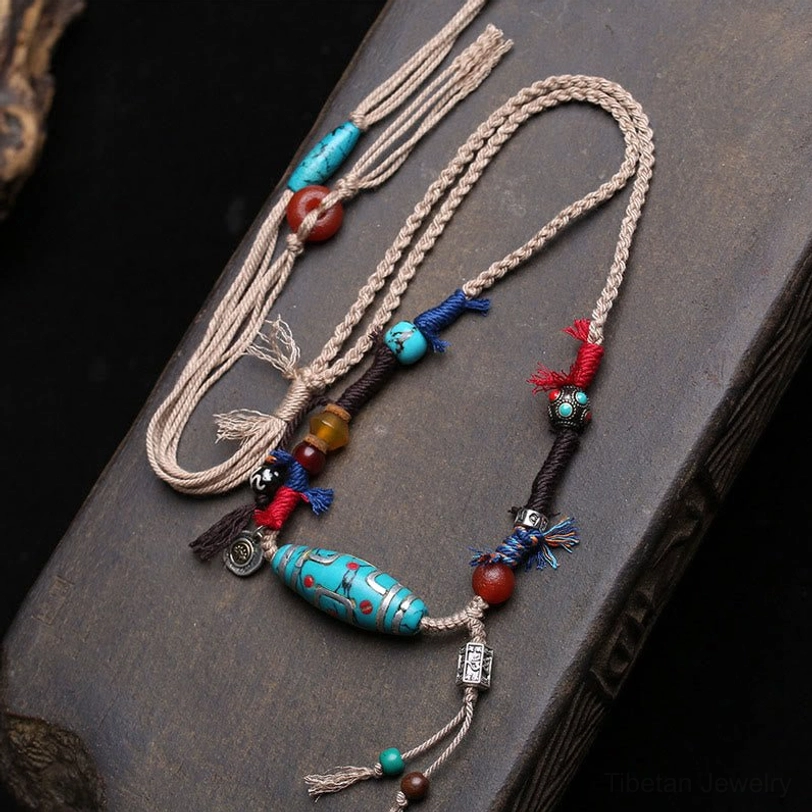 Nine-eye turquoise dzi bead necklace with copper accents on dark wooden surface, authentic Tibetan pendant jewelry