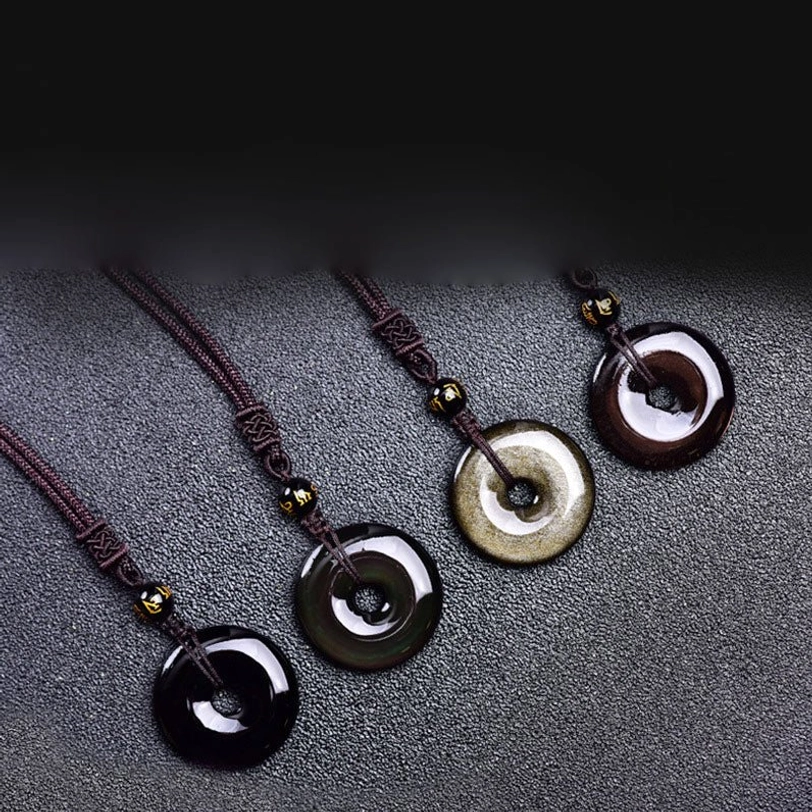 Tibetan obsidian protection necklaces collection - black, gold sheen, and rainbow variants displayed in flat lay on dark textured surface