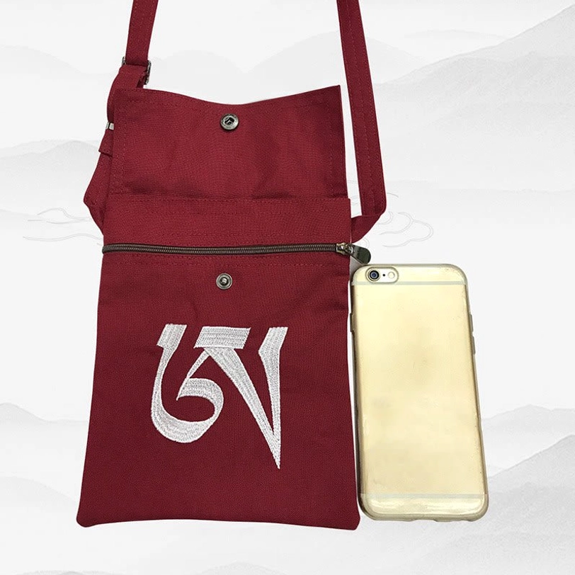 Burgundy Tibetan OM mantra canvas bag with smartphone size reference showing front zipper pocket and white mantra embroidery