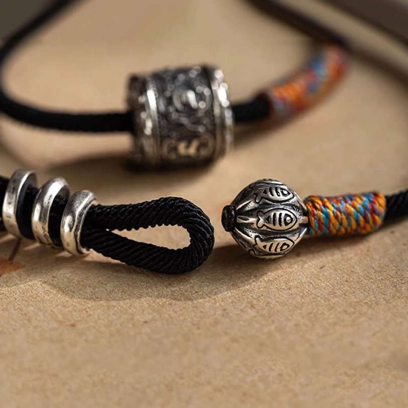 Om Mani Padme Hum Tibetan amulet bracelet end section showing adjustable loop knot and fish-carved bell