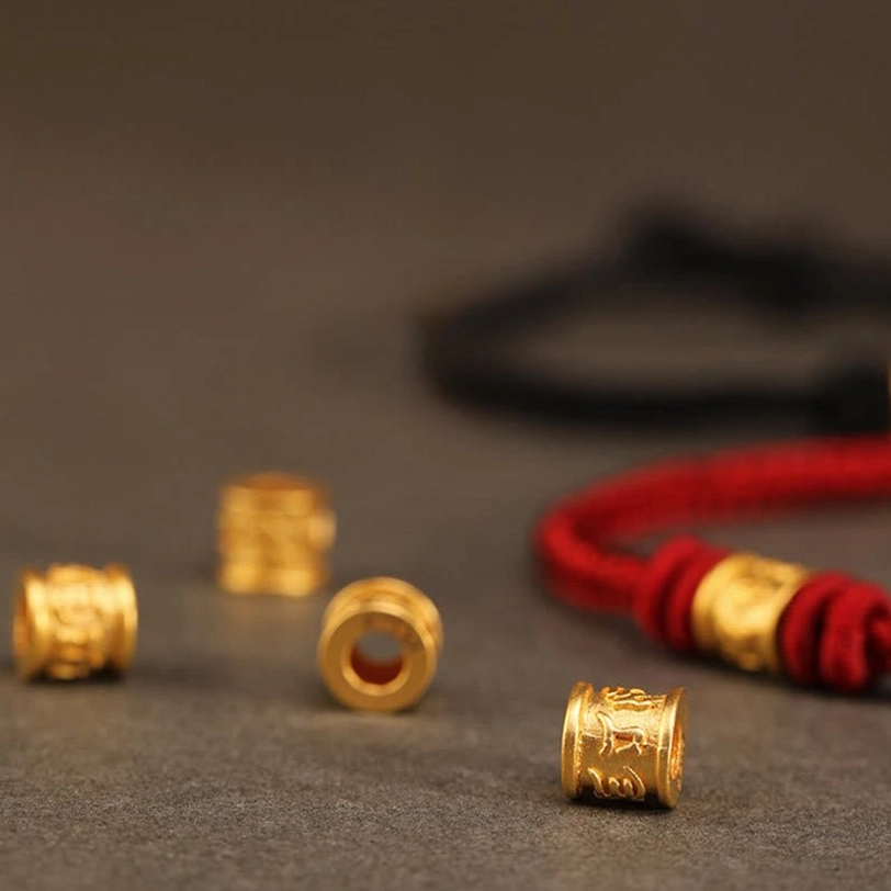 Multiple Tibetan om mani padme hum bracelet charms and red cord samples, showing craftsmanship variety