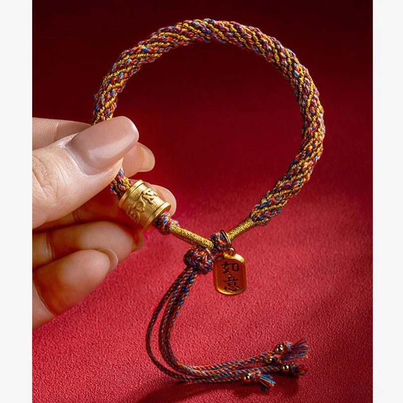 Tibetan lucky bracelet held in hand showing Ruyi charm pendant and tassel end detail