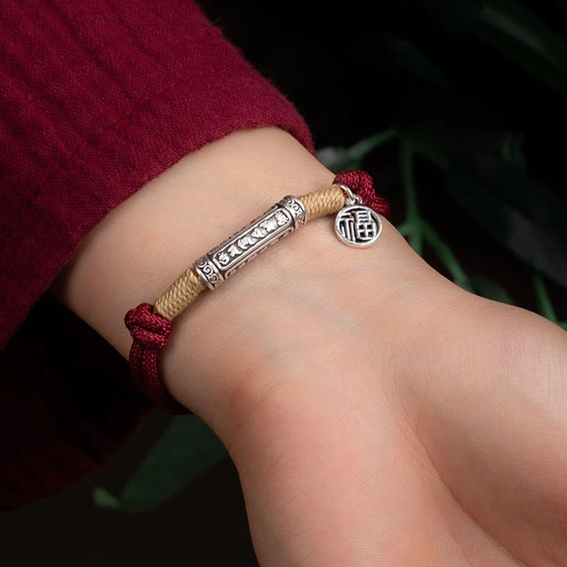 Tibetan om mani padme hum bracelet worn on wrist showing natural fit with green foliage background