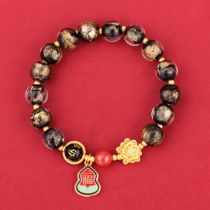 Tibetan Om Mani Padme Hum Liuli glass bracelet with spotted black beads, gold lotus charm, and Fu character enamel pendant on red background