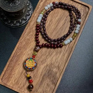 Tibetan Om Mani Padme Hum wood bead necklace with copper enamel pendant displayed on wooden tray