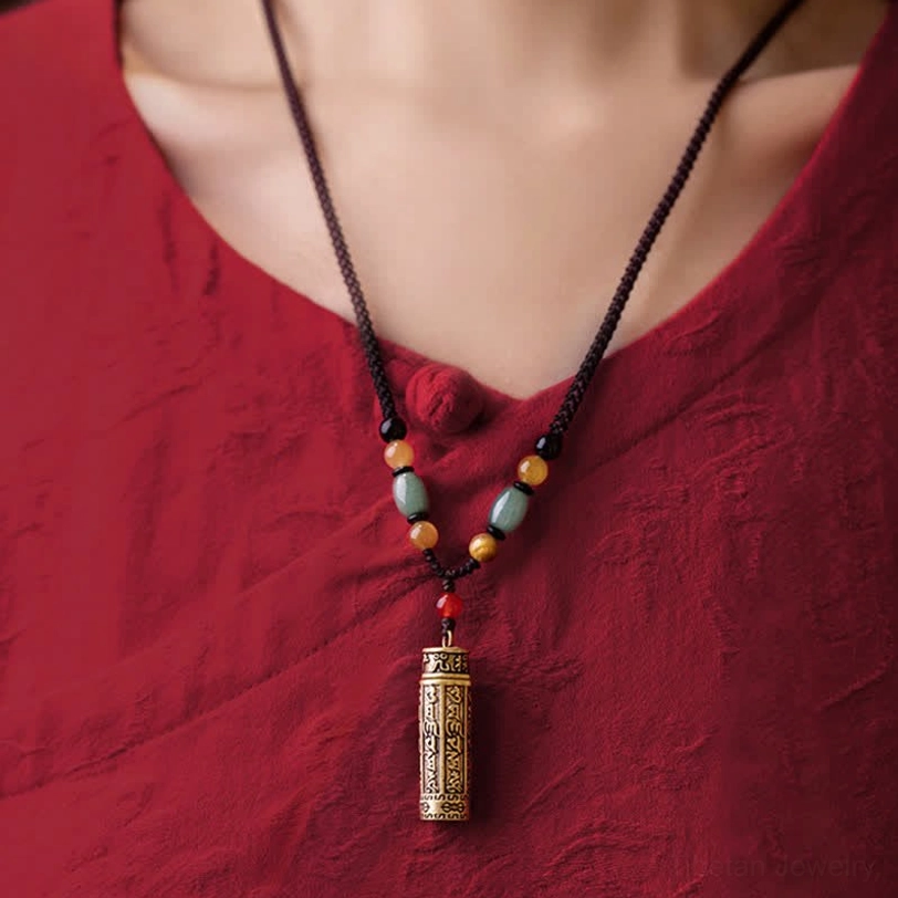 Tibetan spiritual necklace worn on person in red attire, displaying neat beaded chain with engraved mantra pendant