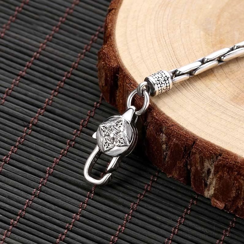 Close-up side view of tibetan silver bracelet chain and carved clasp hardware