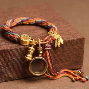 Tibetan Om Mani Padme Hum protection bracelet with multicolor braided rope and gold metal charms displayed on wooden surface
