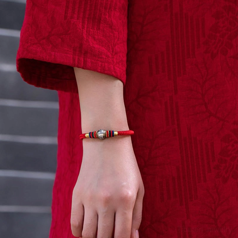 Red Tibetan Om Mani Padme Hum bracelet worn on wrist with traditional red clothing indoor