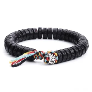 Tibetan Om Mani Padme Hum coconut shell mantra bracelet flat lay overhead view with black engraved beads and colorful tassel clasp on white background