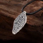 Tibetan Om Mani Padme Hum sterling silver pendant with Dorje Vajra symbol, vintage matte finish on wooden surface