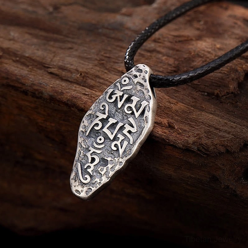 Tibetan Om Mani Padme Hum sterling silver pendant with Dorje Vajra symbol, vintage matte finish on wooden surface