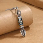 Tibetan Om Mani Padme Hum rotatable pendant with turquoise enamel inlay and silver-tone finish, close-up side view showing vajra hardware details