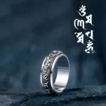 Tibetan Om Mani Padme Hum Pixiu rotatable silver ring with engraved mantras on dark stone backdrop