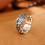 Om Mani Padme Hum Tibetan mantra adjustable open ring, vintage silver finish with carved Sanskrit mantras, three-quarter side view on leather background