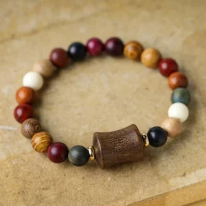 Tibetan Om Mani Padme Hum sandalwood protection bracelet overhead flat lay view with multicolored wooden beads and carved central focal bead on wooden surface