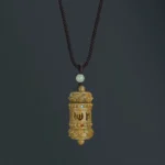 Tibetan green sandalwood Om Mani Padme Hum necklace pendant with Sanskrit carving, overhead studio view showing intricate mantra design