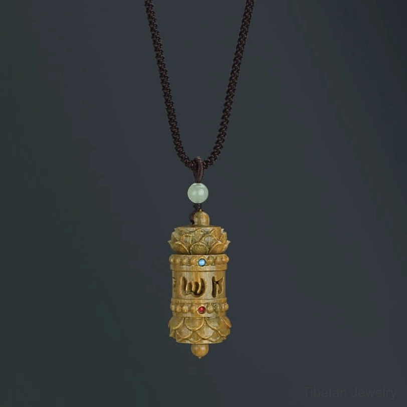 Tibetan green sandalwood Om Mani Padme Hum necklace pendant with Sanskrit carving, overhead studio view showing intricate mantra design