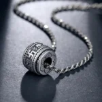 Tibetan Om Mani Padme Hum silver barrel pendant necklace with twisted rope chain, overhead view showing intricate Sanskrit engravings