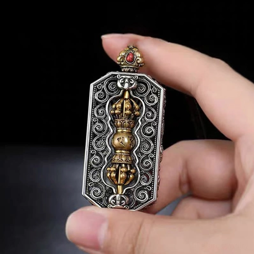 Front view of Tibetan Om Mani Padme Hum dorje vajra pendant held in hand with scroll-patterned border and rotatable golden vajra