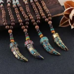 Tibetan Om Mani Padme Hum wenge wood necklace with horn pendant flat lay top view, featuring dark wooden beads and ornate metal pendant with Tibetan script