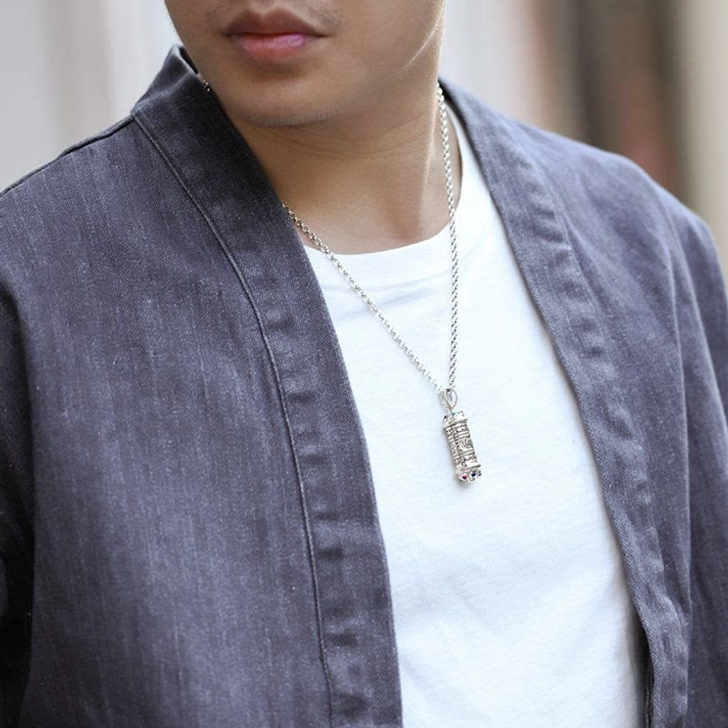 Wearable Tibetan Buddhist pendant necklace styled on body, silver chain resting at lower chest with casual outfit