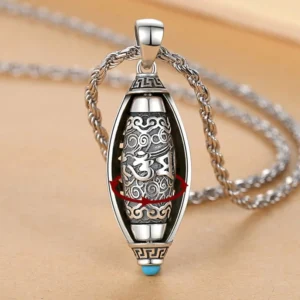 Tibetan Om Mani Padme Hum rotatable pendant necklace with 360-degree rotating inner core, vintage silver finish and blue gem detail on wooden surface
