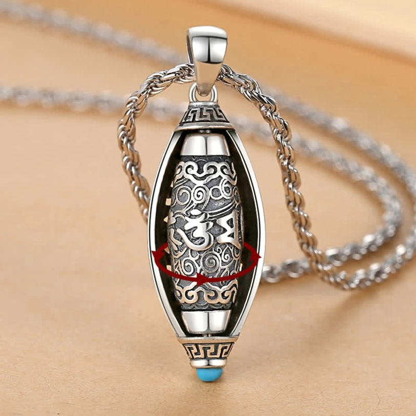 Tibetan Om Mani Padme Hum rotatable pendant necklace with 360-degree rotating inner core, vintage silver finish and blue gem detail on wooden surface
