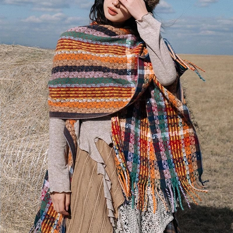 One-shoulder draped Tibetan tassel shawl with colorful stripe patterns and fringed hem, front three-quarter grassland view