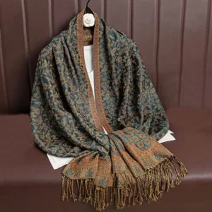 Tibetan jacquard paisley tassel shawl in dark green with brown decorative accents, displayed flat on leather sofa showing intricate woven pattern and frayed hem