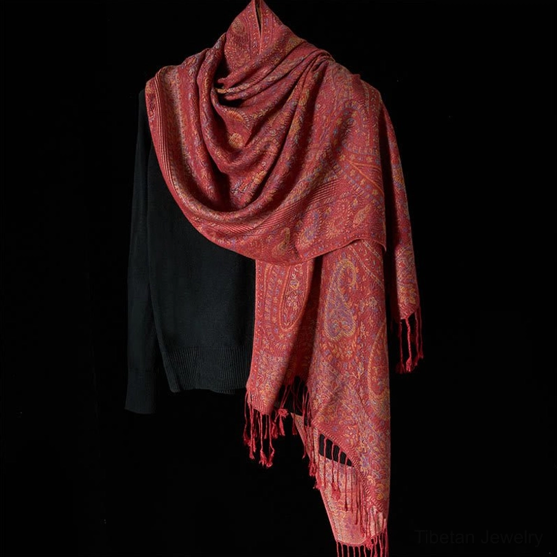Side draped view of Tibetan red paisley scarf with long hanging tassels, demonstrating versatile styling
