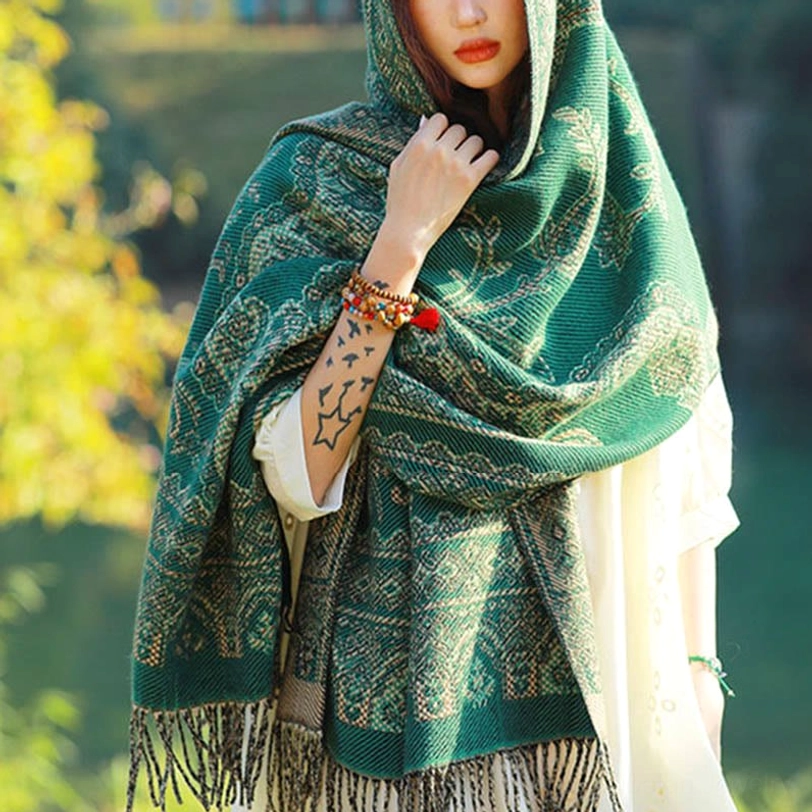 Lakeside setting showing Tibetan paisley shawl worn with matching beaded bracelet, front three-quarter view with tassel trim detail