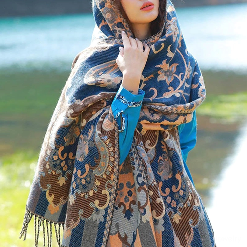 Blue and cream Tibetan jacquard paisley shawl with thermal woven fabric worn on head at lakeside, showing tassel fringe trim