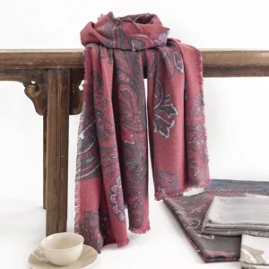Tibetan burgundy paisley pashmina shawl with grey-blue motifs displayed on vintage wooden table with tea setting