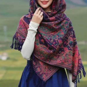 Close-up front view of Tibetan cashew paisley wrap shawl on model with full floral print and tassel hem detail in natural outdoor grassland background