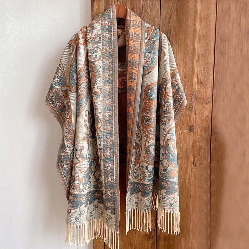 Tibetan paisley tassel shawl with cream fringe in warm retro design, displayed on wooden hanger with natural lighting