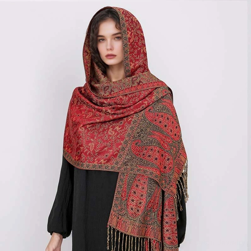 Model wearing crimson red Tibetan jacquard shawl with brown paisley patterns as hooded head wrap, front view showing versatile styling options