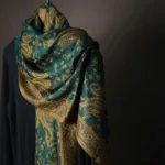 Tibetan paisley cashew flower shawl in dark green displayed on mannequin with gold-brown vintage floral pattern