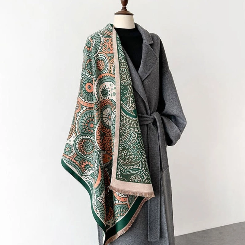Tibetan ethnic paisley shawl draped on mannequin with grey coat and black top, showing green border trim and traditional ethnic pattern