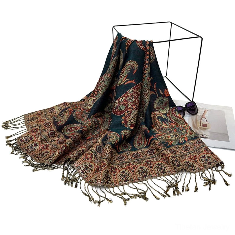 Tibetan paisley shawl flat lay overhead view on metal stand with dark teal base and warm paisley patterns