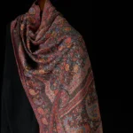 Tibetan paisley tassel shawl in warm brown tones, front three-quarter view showcasing intricate jacquard woven pattern and decorative tassels
