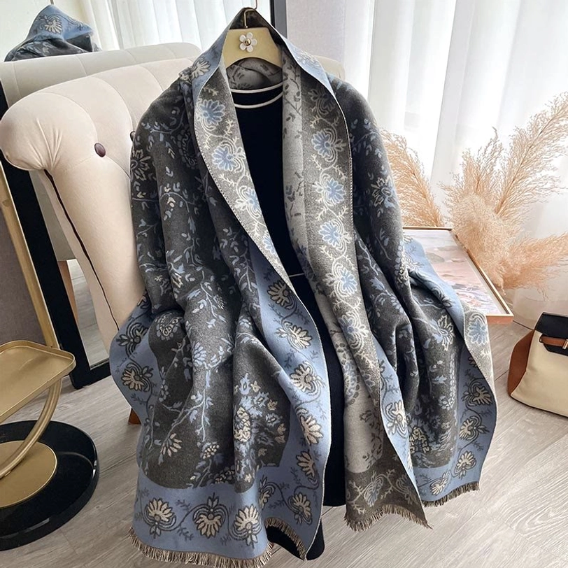 Tibetan paisley shawl with muted grey and blue design hanging on display in clothing space