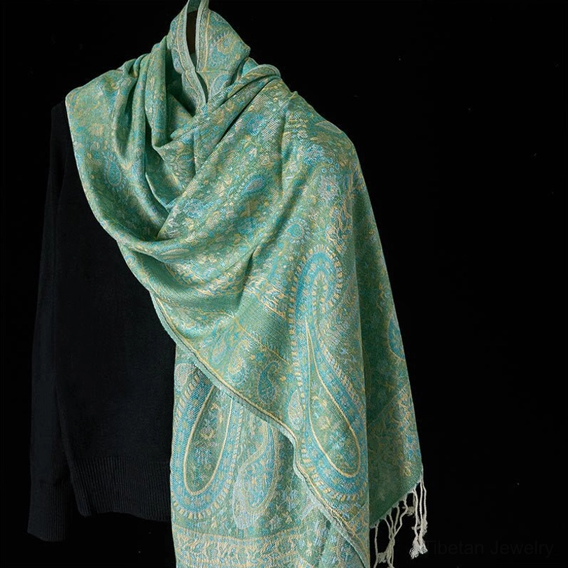 Light sage green Tibetan paisley tassel shawl, front hanging view on dress form with white fringe