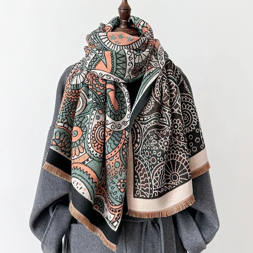 Tibetan ethnic paisley shawl with tassels draped on mannequin with grey wool coat, showing front three-quarter view of reversible geometric pattern