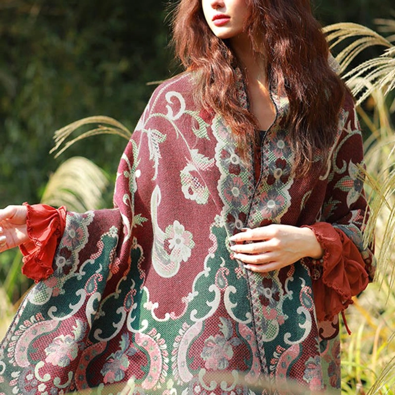 Front view of maroon Tibetan paisley shawl with green and pink floral patterns worn over outfit in outdoor grassy field setting