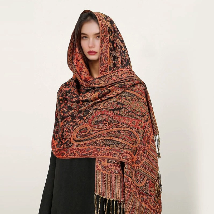 Model wearing dark brown Tibetan paisley shawl with orange-red jacquard patterns and decorative tassel hem, front